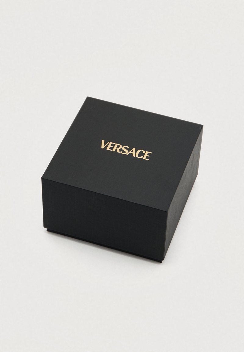 Schwarze quadratische Box aus strukturiertem Material mit einem goldenen "VERSACE"-Logo oben. Die Kanten sind sauber und scharf.