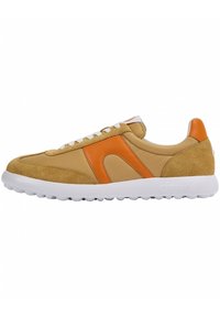 Zapatilla con parte superior de ante y tela en tono beige, con un acento naranja y suela de goma blanca con un patrón texturizado. Diseño con cordones.