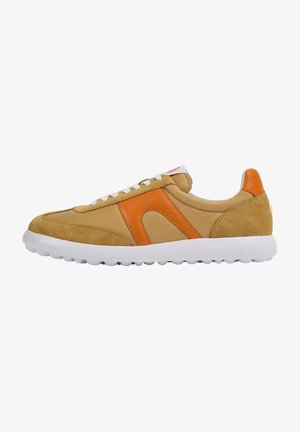 Zapatilla con parte superior de ante y tela en tono beige, con un acento naranja y suela de goma blanca con un patrón texturizado. Diseño con cordones.