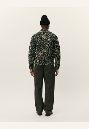 Floral-printed jacket in dark green with red and orange accents, paired with dark green trousers. Features a relaxed fit and long sleeves.