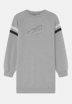 Grå langærmet sweatshirt-kjole med ribstrikkede manchetter, "Tommy 85" tekst på brystet og hvide og sorte striber på overarmene.