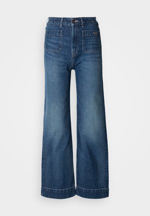 Jeans en denim bleu foncé à jambes larges avec une finition délavée, taille haute, quatre poches, dotés d'une fermeture classique à bouton et glissière.