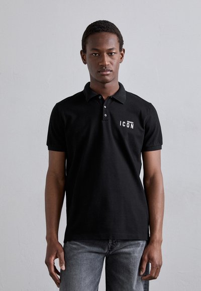 Black polo shirt with a collared design, featuring white "ICON" text on the left chest area. Worn with gray jeans.