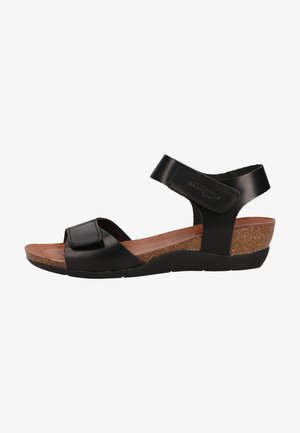 Schwarze Leder-Wedgesandalen verfügen über einen breiten verstellbaren Riemen, eine Kork-Mittelsohle und eine strukturierte Gummisohle für besseren Halt.
