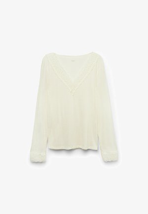 Haut à manches longues crème avec un décolleté en V, orné de délicates finitions en dentelle et d'accents en dentelle aux poignets, fabriqué à partir d'un tissu doux et léger.