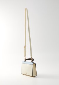 Petit sac à main rectangulaire crème avec rabat bleu clair, poignée supérieure noire et longue bandoulière crème réglable sur fond blanc.