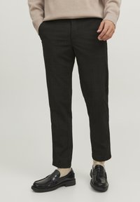 Pantaloni a quadri neri con vestibilità su misura, lunghezza crop, texture morbida e tasche laterali, abbinati a mocassini neri e calzini crema.
