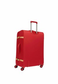 Valise rigide rouge avec des sangles beige, quatre roulettes pivotantes noires et rouges, une poignée latérale et une poignée télescopique argentée extensible.