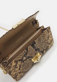 Brun slangeskindspræget håndtaske med en guldtonet lås, kædestrop og en beige foring. Har en lynlås lomme og logo prægning indeni.