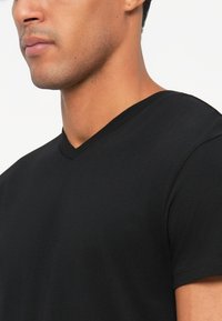 Black V-neck t-shirt made of soft fabric with short sleeves and a fitted design, showcasing a smooth texture and clean neckline.