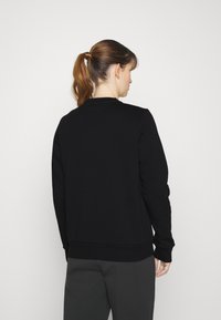 Felpa nera con scollatura rotonda, polsini e orlo a coste. Texture liscia, caratterizzata da un design semplice senza motivi o accessori visibili.