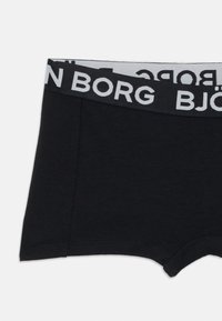 Črne bombažne bokserice z belim elastikom, na katerem je napis "BJÖRN BORG". Tkanina se zdi mehka in ima gladko teksturo.
