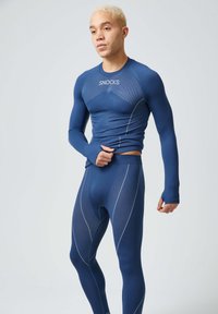 Top ajustado de manga larga en azul marino y leggings hechos de tela elástica, con costuras en gris claro y un logo en el pecho.