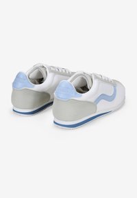 Zapatillas blancas y gris claro con acentos azules, que cuentan con una parte superior de cuero suave, punta redondeada y detalles texturizados en el talón.