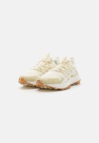 Lichtbeige sportieve schoenen met een textuur van gaas aan de bovenkant, versterkte neus en een bruine rubberen zool. Heeft een gelaagd ontwerp en vetersluitingdetails.
