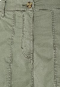 Kalhoty z bavlněné směsi ve světlé zelené barvě s diagonální tkanou strukturou, s jednou přední kapsou a kruhovým hnědým knoflíkem.