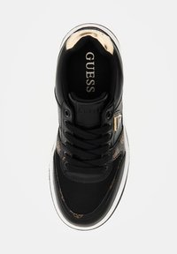 Sneaker nera con mesh texturizzato nero e dettagli in pelliccia sintetica. Presenta lacci neri e un accento dorato di lato, con una suola bianca.