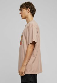 Light pink cotton t-shirt with a relaxed fit, round neckline, short sleeves, and graphic design featuring bold colors on the front.