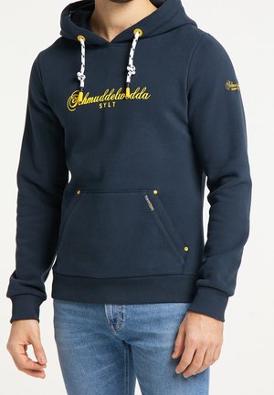 Sweat à capuche bleu marine en coton avec une poche frontale, doté de cordons de serrage et de coutures jaunes, ainsi que d'un logo sur la poitrine et la manche.