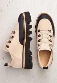 Scarpe in camoscio beige con suole in gomma nera e design zigzag pronunciato. Presentano occhielli in metallo e lacci beige per una vestibilità sicura.