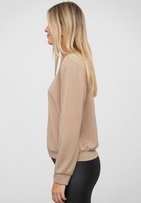 Beige lange mouw sweatshirt met een relaxte pasvorm, ribgebreide manchetten en zoom. Soepele textuur, eenvoudig ontwerp zonder patronen of accenten.