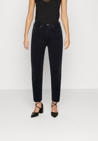 Mörkblå sammetbyxor med slim fit, hög midja och framfickor, kombinerat med svarta sandaler med klack och remmar.