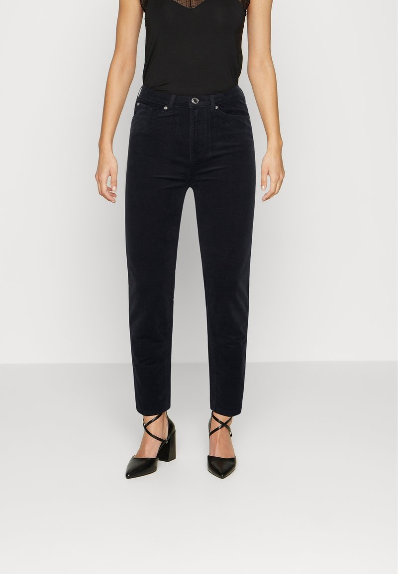 Mörkblå sammetbyxor med slim fit, hög midja och framfickor, kombinerat med svarta sandaler med klack och remmar.