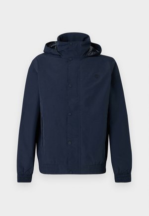 Tamsiai mėlyna gobtuvu striukė su spaudžiamais užsegimais, elastinėmis rankogaliais, šoninėmis kišenėmis ir mažu siuvinėtu logotipu ant krūtinės.