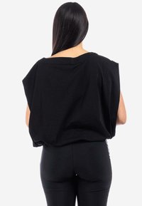 T-shirt nera oversize realizzata in cotone morbido, con maniche ampie e vestibilità comoda, dotata di girocollo alto e texture liscia.