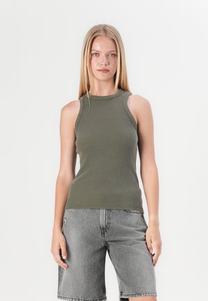 Oliven grønn ribbet T-skjorte med høy hals og ermeløs design, sammen med grå denimshorts med en frynset kant.