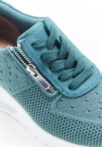 Sneaker in maglia verde acqua con superficie testurizzata, chiusura con lacci e zip laterale metallica. La suola in gomma bianca offre un contrasto.