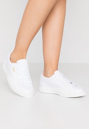 Baskets blanches de sport avec une tige en cuir lisse, semelle en caoutchouc texturé, lacets sur le devant et un branding subtil sur le côté.