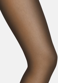 Collant marroni trasparenti con una superficie liscia e una finitura leggermente riflettente, progettati per adattarsi alla forma della gamba.