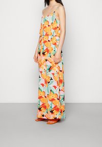 Floral maxi-jurk van een lichte stof. Kenmerken zijn levendige oranje, roze en groene bloempatronen. Inclusief dunne spaghettibanden en een elastische tailleband.
