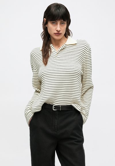 Pruhovaná polokošeľa s dlhým rukávom v krémovej a čiernej farbe, s golierom a voľným strihom, doplnená o čierne vysokovýpásové nohavice a opasok.