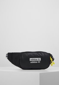Bolso de cinturón negro de Adidas con dos logotipos blancos de Adidas, tiradores de cremallera amarillos y correa ajustable con detalles de rayas blancas.