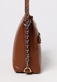 Borsa a mano in pelle marrone con vista laterale, dotata di tracolla a catena, dettagli in metallo dorato e texture liscia.