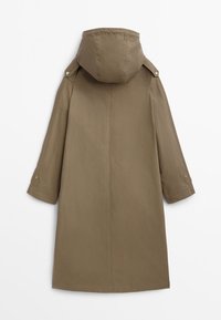 Olive green, knee-length raincoat with a hood, structured design, loose sleeves, and side buttons for adjustment. Smooth texture, minimalist style.