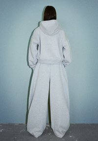 Gray sweatshirt with a hood and oversized sleeves, paired with wide-leg gray sweatpants, both featuring a soft, textured fabric.