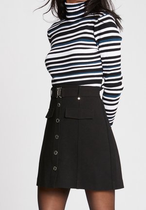 Zwarte A-lijn rok met een sluiting aan de voorkant, twee zakken en een ceintuur in de taille. Gestreepte coltrui in zwart, wit en blauw.
