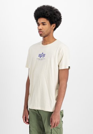 Cremefarvet bomulds T-shirt med et lilla logodesign centreret på brystet. Korte ærmer og en afslappet pasform. Accentueret med et logopatch på ærmet.