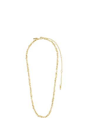 Młody mężczyzna o kręconych włosach i niebieskich oczach, noszący złoty łańcuszek i białą prążkowaną koszulę na jednolitym tle.