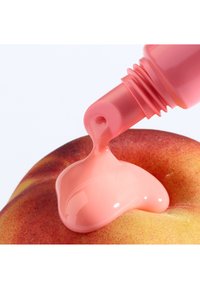 Un liquide rose étant distribué d'un tube sur la surface d'une pomme rouge, mettant en valeur une texture brillante et une consistance lisse.
