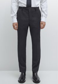 Mörkgrå byxor med rak skärning, med knappstängning, sidfickor och jämn tygstruktur. Matchas med svarta skor.