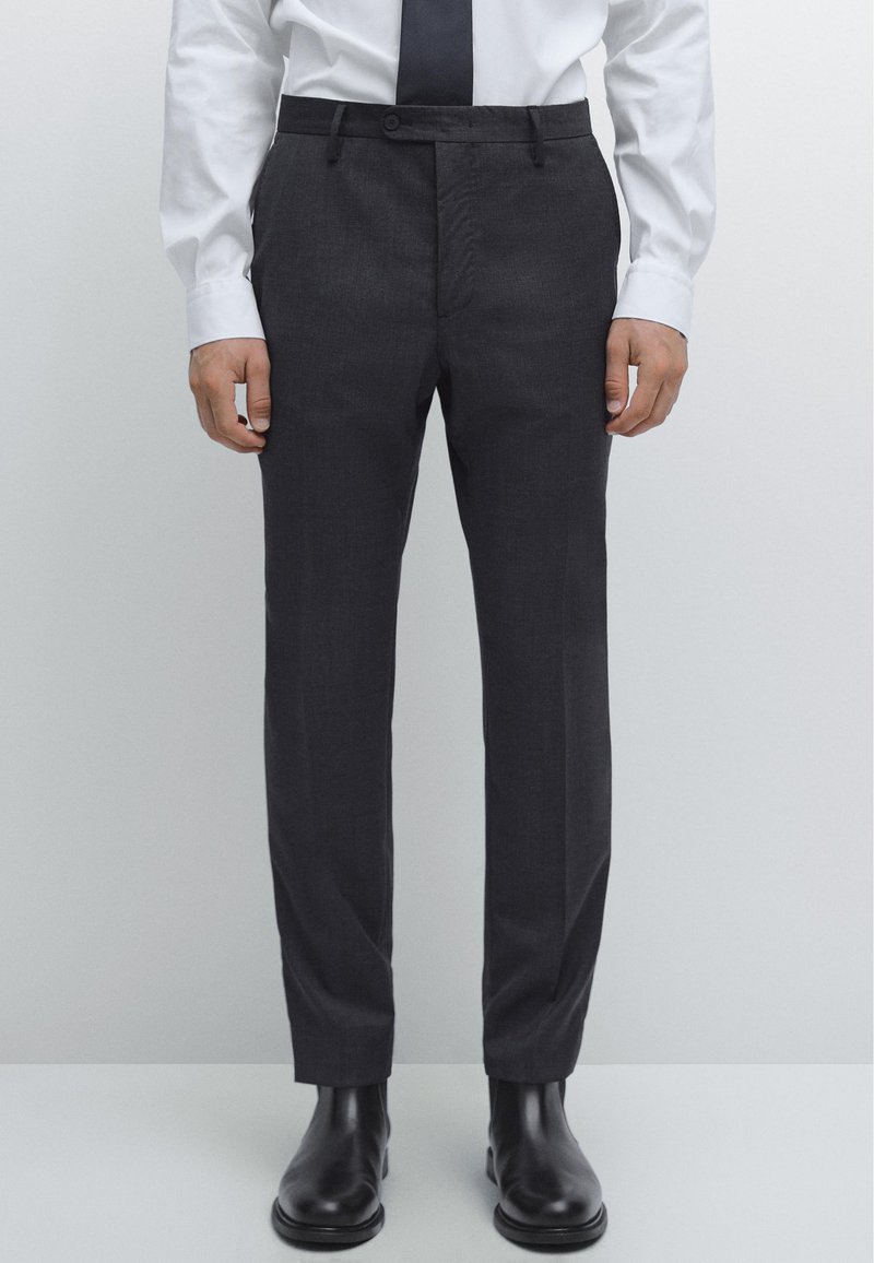 Mörkgrå byxor med rak skärning, med knappstängning, sidfickor och jämn tygstruktur. Matchas med svarta skor.