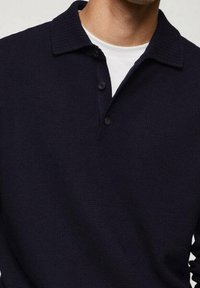 Navyblaues Poloshirt aus strukturiertem Strickstoff, mit Kragen, Drei-Knopf-Leiste und kurzen Ärmeln.