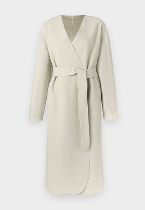 Lång, omlottkappa i ljust beige tyg med djup V-ringning, skärp i midjan och vida ärmar. Minimalistisk design med jämn textur.