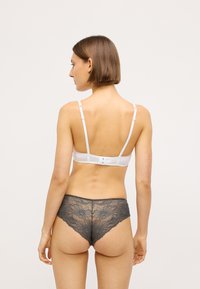 Bra bianco con spalline regolabili e chiusura a gancio, abbinato a culotte grigie in pizzo con motivi floreali e bordi scallop.