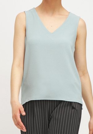 Personne portant un haut sans manches bleu clair à col en V et un pantalon noir à fines rayures blanches verticales, vue des épaules aux hanches.