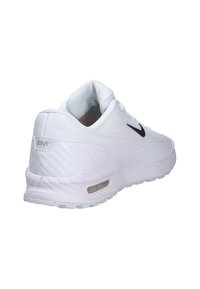 Zapatilla deportiva blanca con parte superior de malla, logo negro, cuello acolchado y amortiguación de aire visible en la suela. Acabados laterales texturizados añaden detalle.